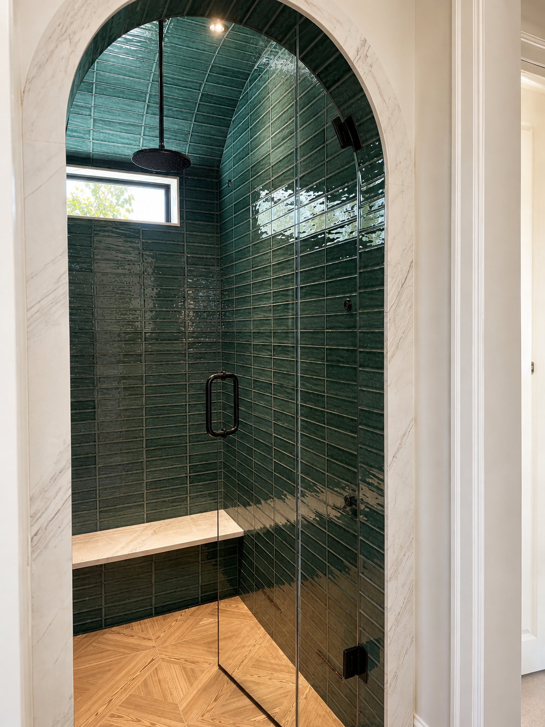 Master steam shower with full arched marble entry, floor-to-ceiling forest green glossy tile across vault, teak parquet floor, built-in bench, frameless glass door, and matte black ceiling rainfall head — Voorhies Residence, Bend Oregon
