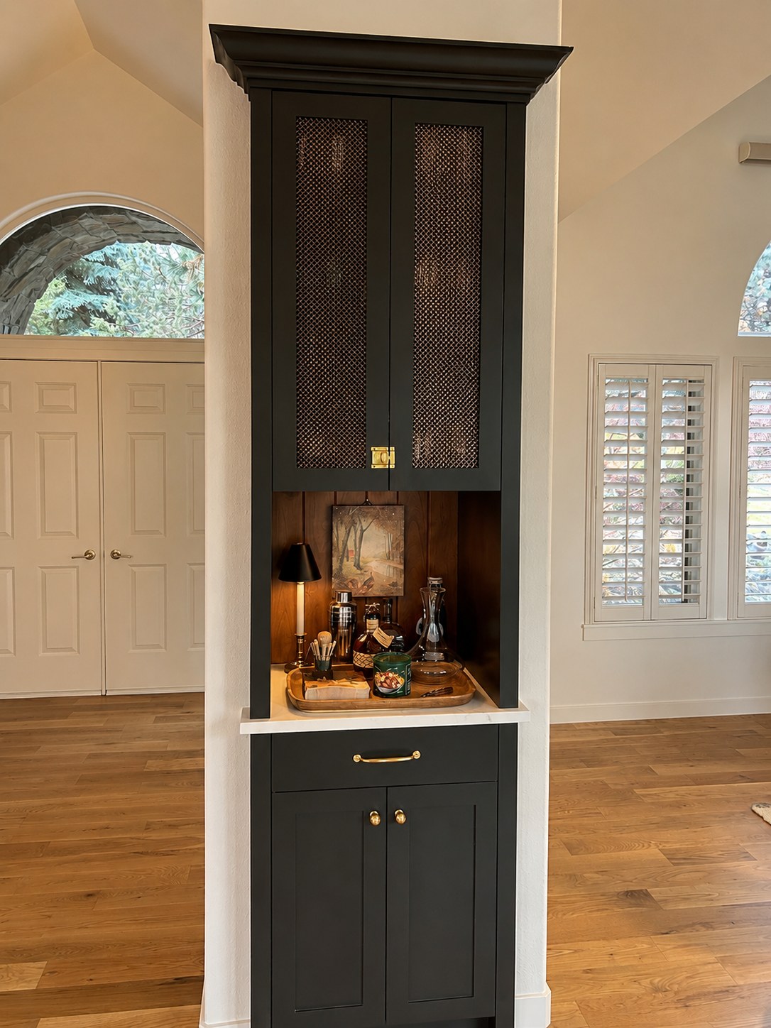 Custom built-in bar cabinet with charcoal shaker doors, cane mesh upper panels, brass hardware, and marble countertop — Kuck Residence, Awbrey Glen Bend Oregon