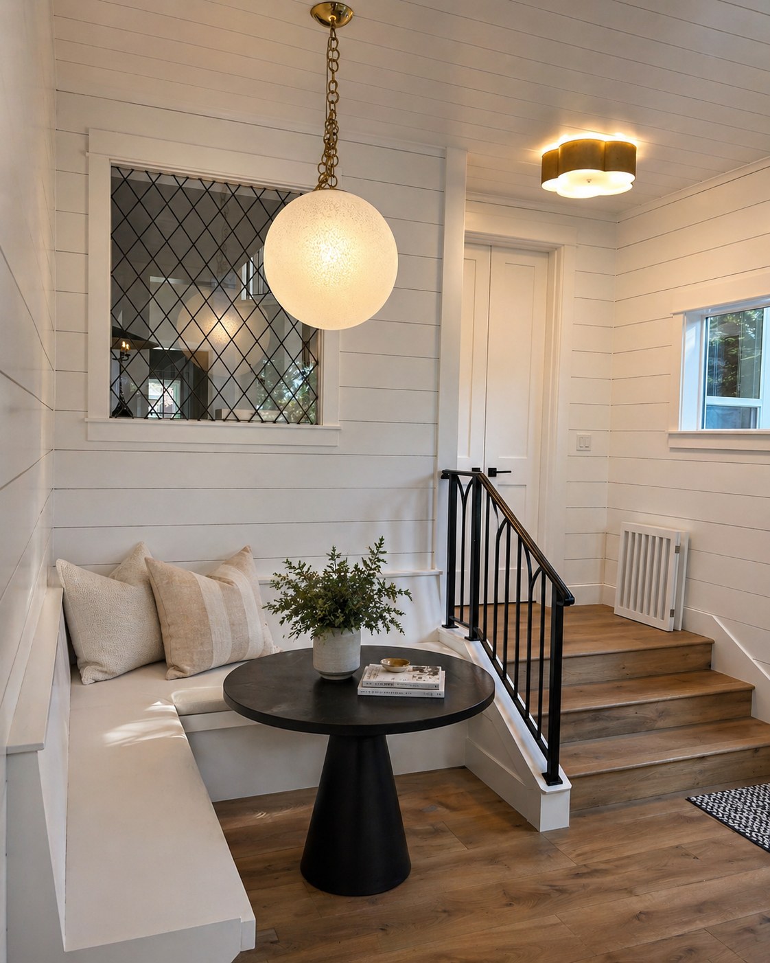 Built-in bench nook with shiplap walls, globe pendant brass chain, leaded diamond window, and iron stair railing — Broken Top addition, Bend Oregon